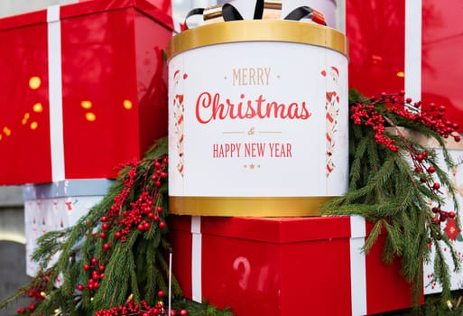 Against the background of a Christmas tree and decorations, there are many large, bright and beautiful red gift boxes. Christmas and New Year 2023-2024