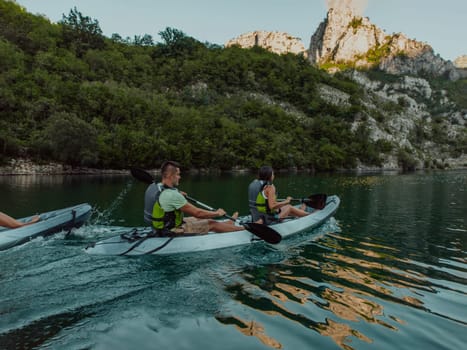 A group of friends enjoying fun and kayaking exploring the calm river, surrounding forest and large natural river canyons during an idyllic sunset