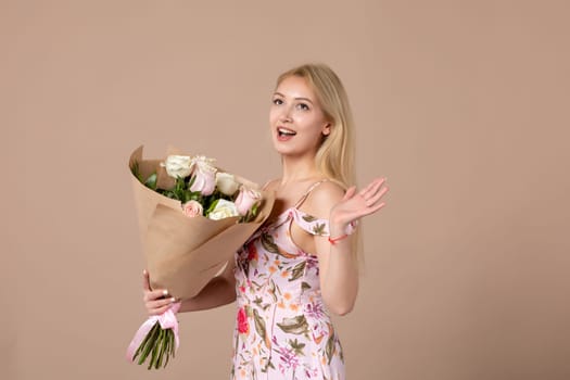 front view young female holding bouquet of beautiful roses on brown background feminine sensual woman march gift marriage equality