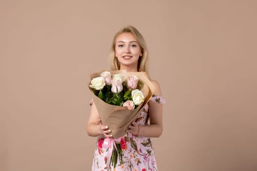 front view young female holding bouquet of beautiful roses on brown background feminine sensual woman horizontal march gift equality