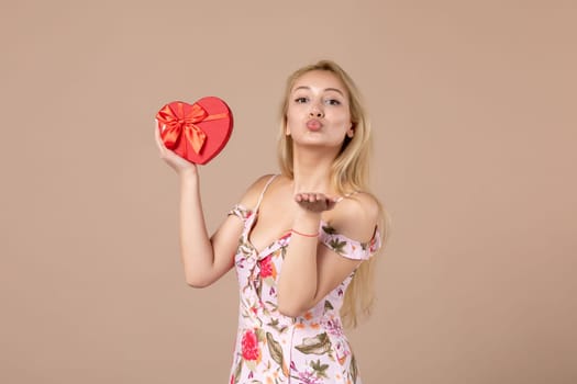 front view young female holding red heart shaped present on brown background feminine sensual money march woman shopping equality marriage