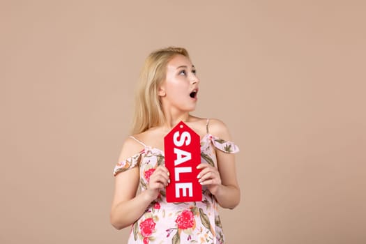 front view young female holding red sale nameplate on brown background money march horizontal feminine equality shopping woman