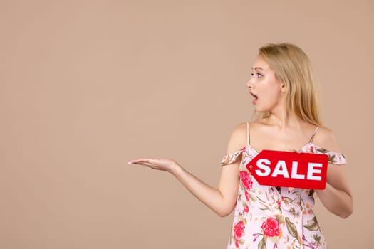 front view young female holding red sale nameplate on brown background money march horizontal sensual shopping woman equality