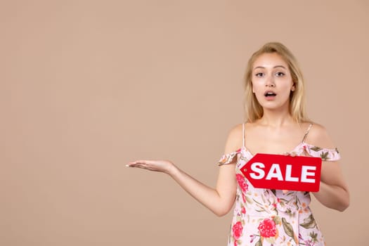 front view young female holding red sale nameplate on brown background money march horizontal shopping woman equality feminine