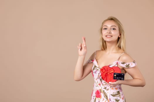 front view young female posing with red heart shaped present and bank card on brown background money march horizontal woman feminine equality