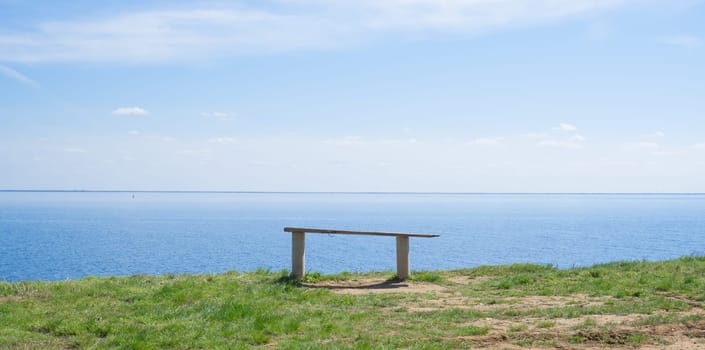 Wooden bench on the shore of the blue sea, lake on a summer sunny day