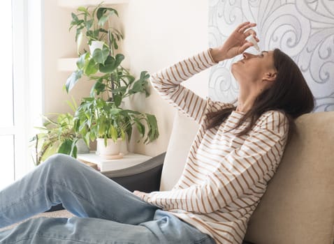 Head shot young caucasian woman using medical eyes drops suffering from dry eyes syndrome or curing ophthalmology disease at home. Unhealthy millennial lady having blurred eyesight, treating eyes