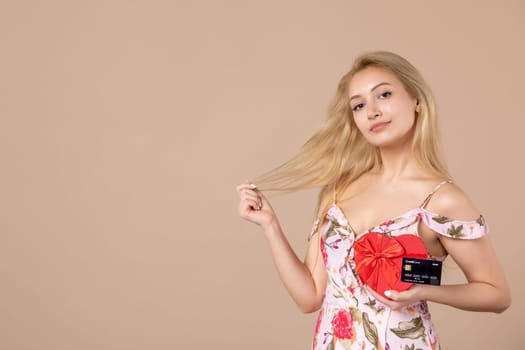 front view young female posing with red heart shaped present and bank card on brown background money equality sensual march horizontal woman