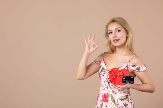 front view young female posing with red heart shaped present and bank card on brown background money sensual march horizontal feminine equality