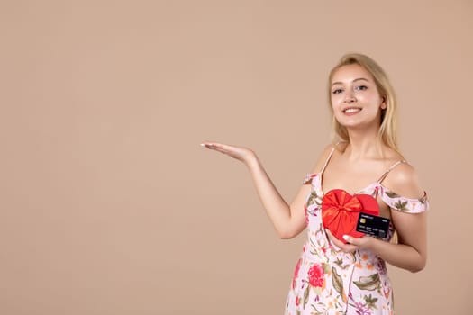 front view young female posing with red heart shaped present and bank card on brown background sensual woman feminine march equality horizontal