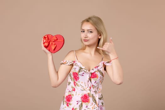 front view young female posing with red heart shaped present on brown background feminine sensual money march woman shopping equality horizontal marriage