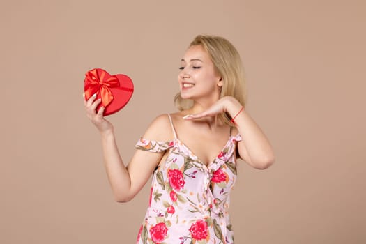 front view young female posing with red heart shaped present on brown background feminine sensual money march woman shopping equality marriage