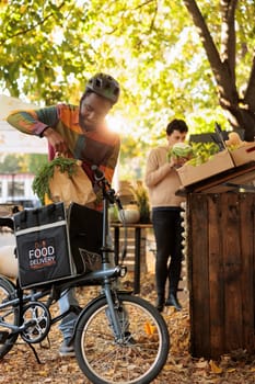 Deliveryman with thermal backpack picking up fresh produce order, working with small business owner and selling organic products. Farmers going online to sell healthy fresh bio farm veggies.