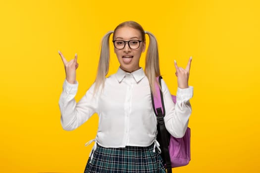 world book day happy school girl with poinytails showing rock sign on yellow background