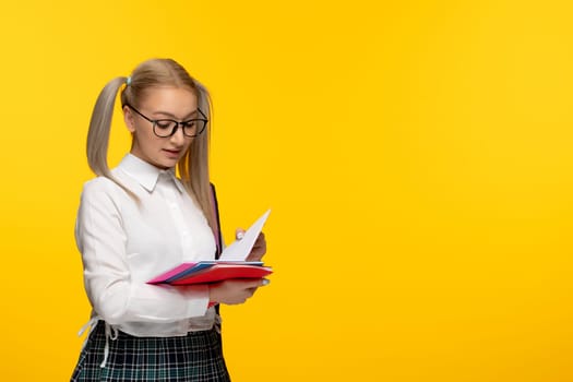world book day blonde schoolgirl with ponytails reading a notebook
