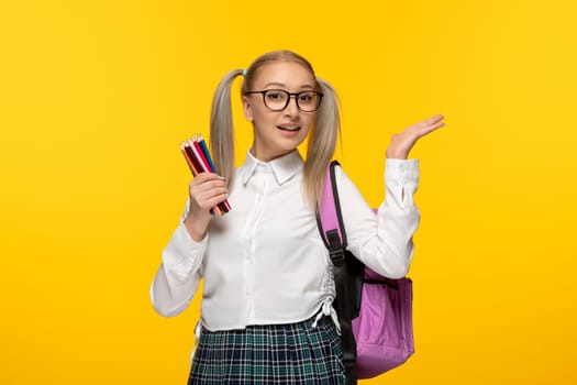 world book day cheering blonde student with pony tails on yellow background holding a lot of pencils