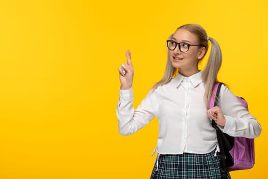 world book day cute happy schoolgirl crossed fingers in uniform yellow background