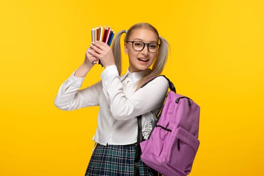 world book day cute student in uniform holding colorful pencils on yellow background