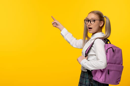 world book day excited blonde student pointing left in glasses and pink backpack