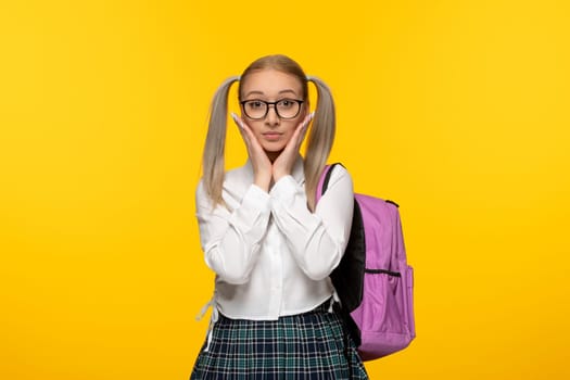 world book day excited school girl in uniform with pink backpack on yellow background