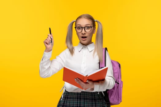 world book day focused student holding a pen and a book on yellow background