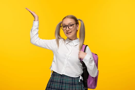 world book day happy schoolgirl with cute backpack on yellow wallpaper