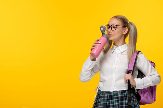 world book day schoolgirl with pony tails drinking from pink flask