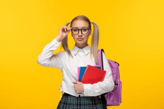 world book day serious blonde schoolgirl with pony tails wearing pink backpack and glasses