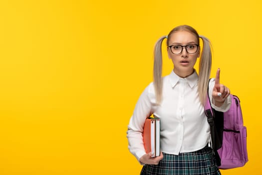 world book day serious blonde student showing stop hand gesture on yellow background