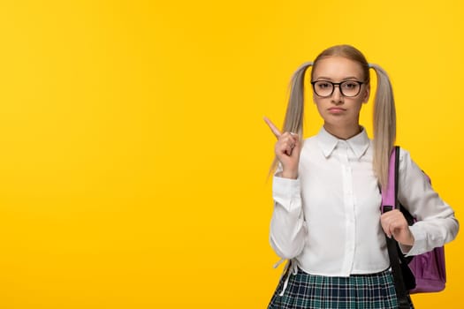 world book day serious school girl with ponytails pointing finger with backpack