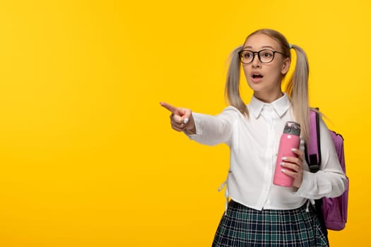 world book day shocked school girl with pink flask on yellow background