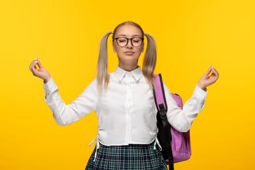 world book day smart blonde schoolgirl in uniform and pink backpack showing zen sign gesture