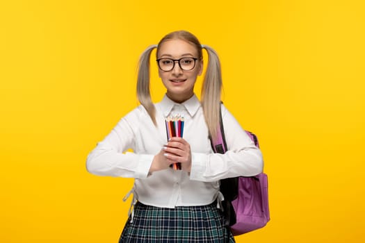 world book day smiling cheering blonde schoolgirl holding pile of colorful pencils