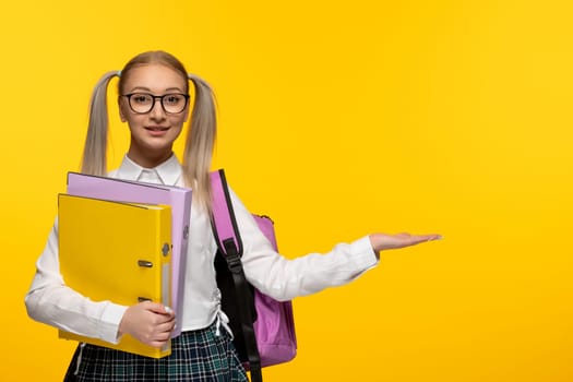 world book day smiling school girl in uniform on yellow background with backpack