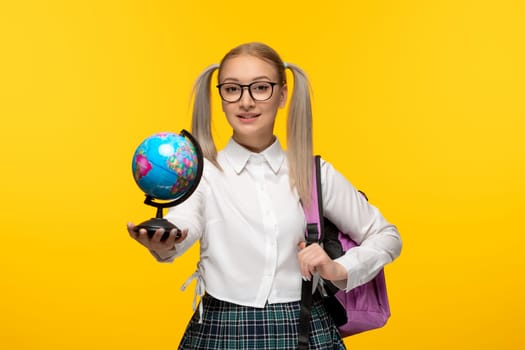 world book day smiling school girl in white shirt holding a globus on yellow background