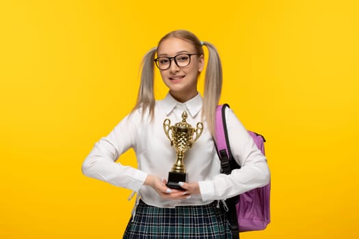 world book day smiling schoolgirl winning trophy and wearing pink backpack