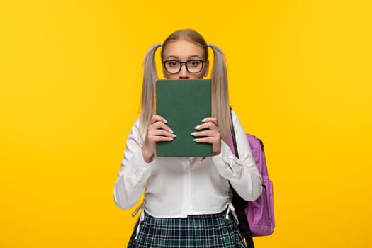 world book day surprised schoolgirl in uniform covering face with books
