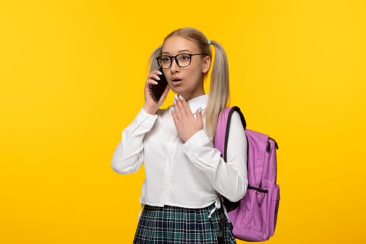 world book day surprised schoolgirl with pink backpack talking on the phone