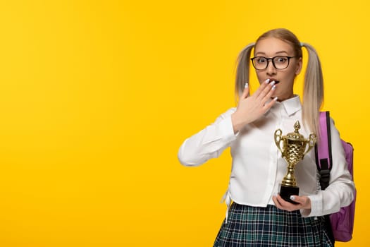 world book day surprised schoolgirl with pony tails holding a golden trophy