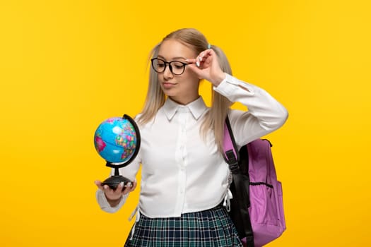 world book day thinking blonde school girl with pony tails and pink backpack holding a globus