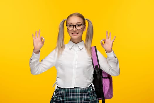 world book day young girl showing okay sign with pink backpack