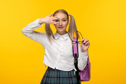 world book day young schoolgirl covering face with the hand on yellow background