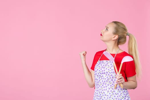 front view young housewife in cape holding spoons on pink background horizontal profession duty job worker wife cutlery occupation