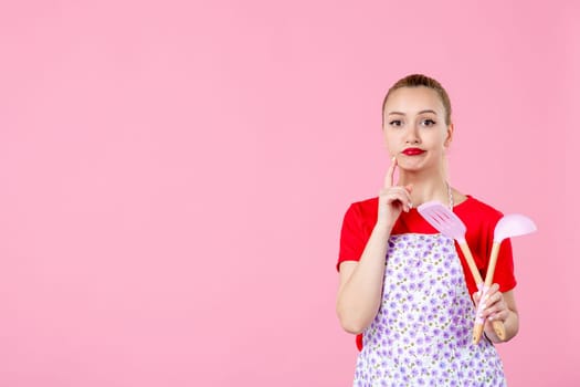 front view young housewife in cape holding spoons on pink background horizontal profession occupation duty job worker uniform cutlery