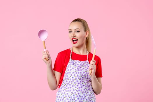front view young housewife in cape holding spoons on pink background horizontal uniform duty occupation profession job wife worker