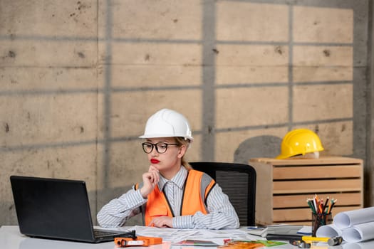 engineer blonde young cute smart girl civil worker in helmet and vest thinking of project