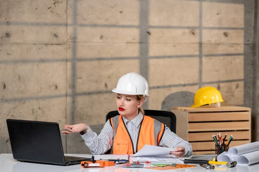 engineer smart young cute blonde girl civil worker in helmet and vest concentrated