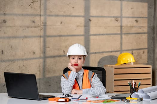 engineer smart young cute blonde girl civil worker in helmet and vest thinking