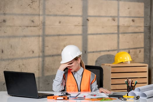 engineer smart young cute blonde girl civil worker in helmet and vest very sleepy