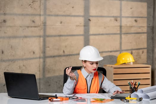 engineer civil worker in helmet and vest smart young cute blonde girl focused on project